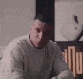 a man in a white sweater is sitting in a living room .
