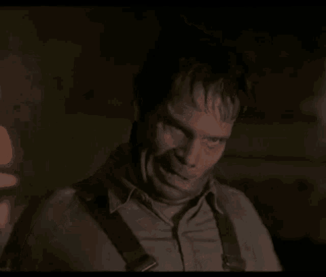a man with a scar on his face is holding a knife in his hand .