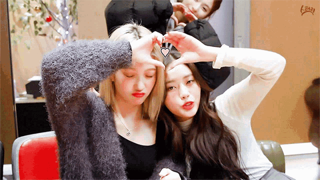 two girls are making a heart shape with their hands and the word love is on the bottom
