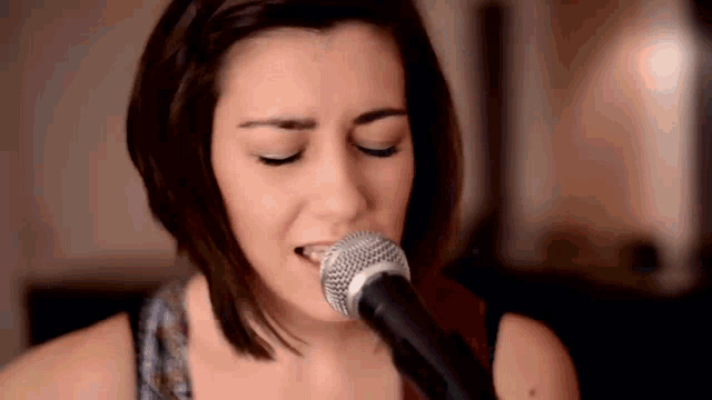 a woman singing into a microphone with her eyes closed .