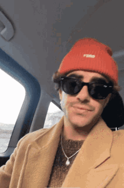 a man wearing a red beanie and sunglasses is smiling