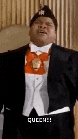 a man in a tuxedo and bow tie is standing in front of a curtain .