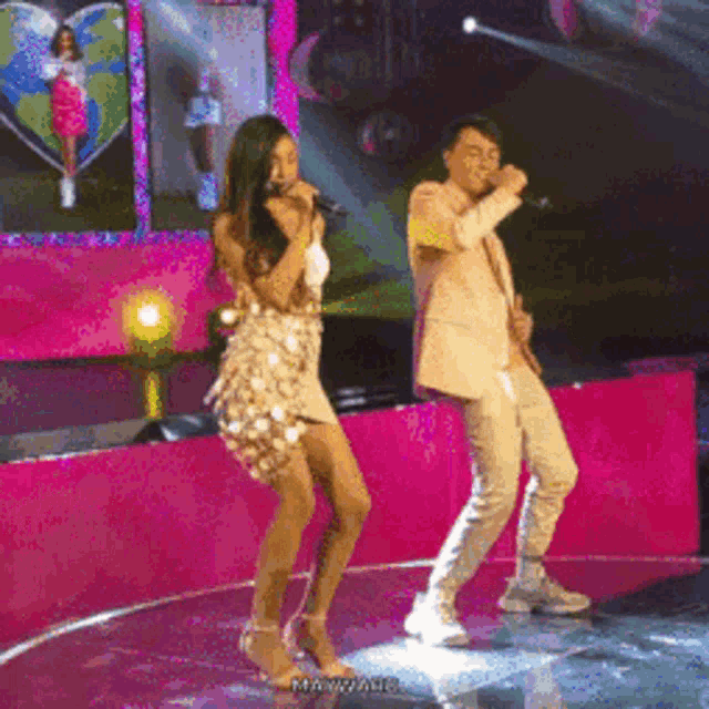 a woman singing into a microphone next to a man dancing