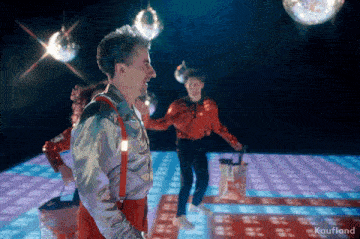 a man and woman are dancing on a disco floor with kaufland written on the bottom