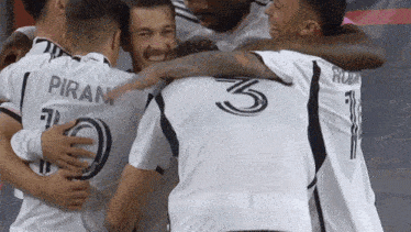a group of soccer players are hugging each other one of whom has the number 3 on his back