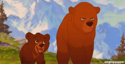 a couple of bears standing next to each other in a field with mountains in the background .
