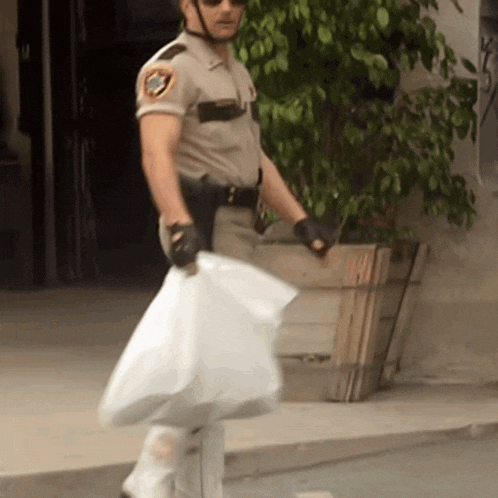 a man in a sheriff 's uniform carrying a white bag