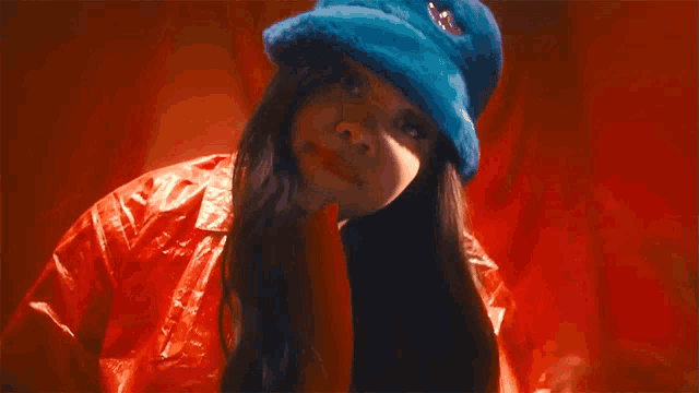 a woman wearing a red jacket and a blue hat is making a funny face .