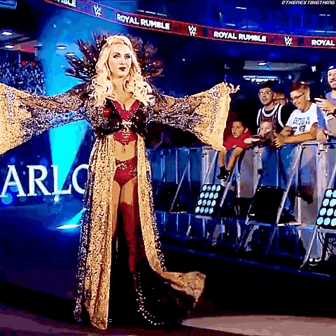a woman in a long dress is standing in front of a crowd of people .
