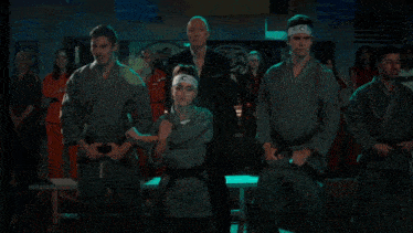 a group of people in karate uniforms stand in front of a sign that says ' karate ' on it