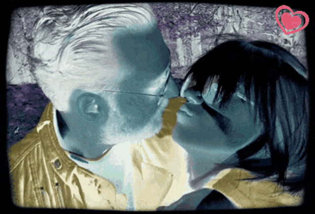 a man and a woman are kissing with a heart in the background