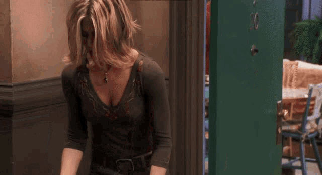 a woman is standing in front of a green door in a hallway .