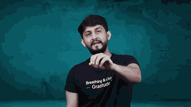 a man wearing a black shirt that says breathing & lvir gratitude