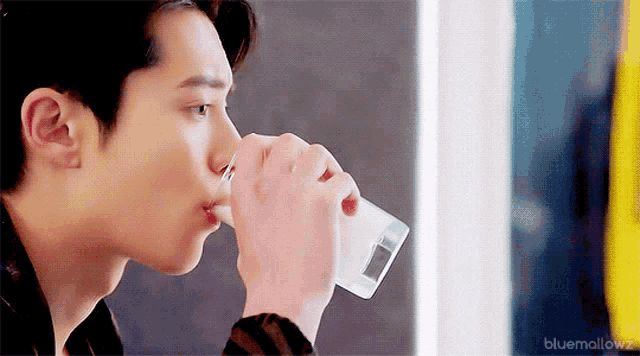 a man is drinking a glass of water from a glass .