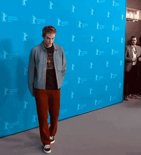 a man is standing in front of a blue wall that says internationale internationale berlin