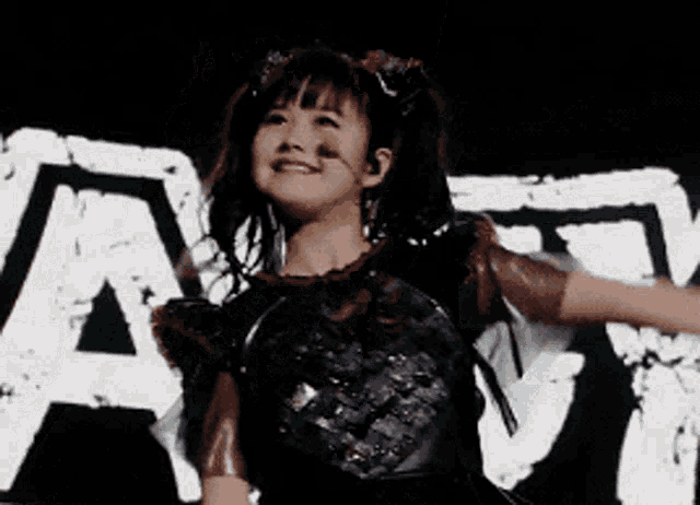 a woman in a black and red outfit is dancing in front of a large letter a