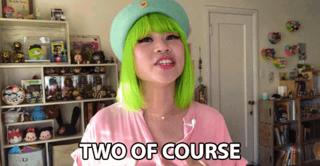 a woman with green hair is wearing a pink shirt and a green hat and says two of course