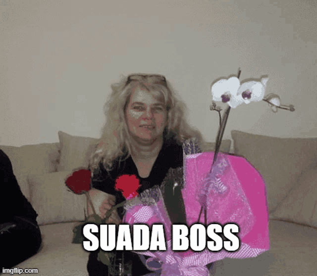 a woman sitting on a couch holding flowers and a pink bag that says suada boss