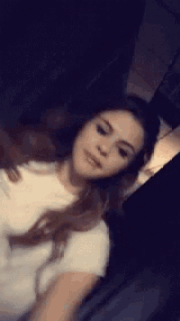 a woman in a white t-shirt is taking a selfie .