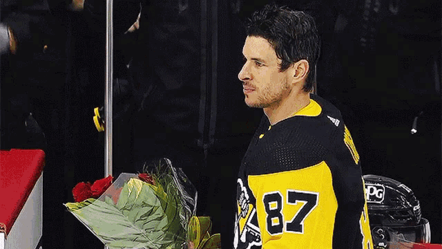 a hockey player with the number 87 on his jersey is holding a bouquet of flowers