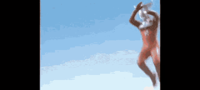 a man in a red superhero costume is jumping in the air against a blue sky .