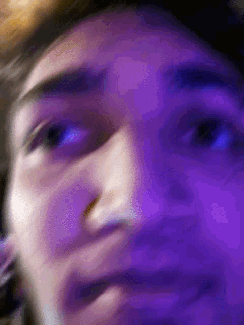 a close up of a person 's face with purple lights in the background