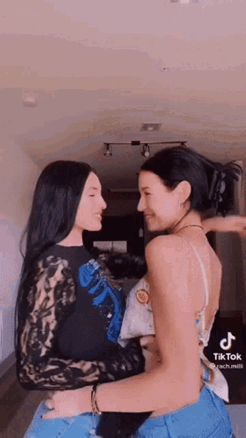 two women are hugging each other and looking at each other .