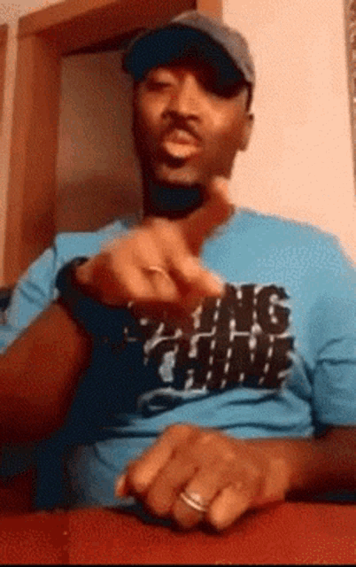 a man wearing a hat and a blue shirt that says ' king ' on it