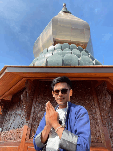 a man wearing sunglasses is standing in front of a statue