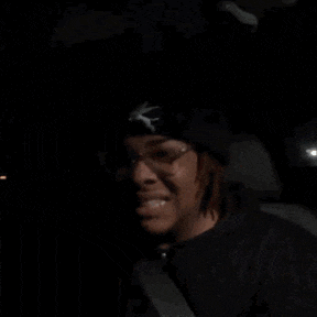 a young man wearing glasses and a hat gives a thumbs up