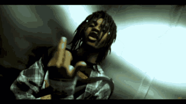 a man with dreadlocks is giving a middle finger