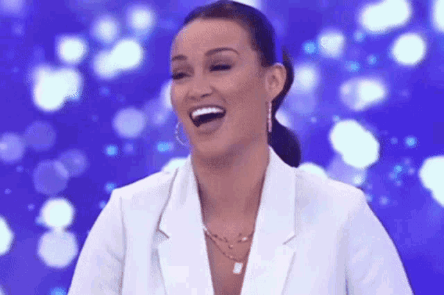 a woman in a white jacket is laughing and smiling on a blue background .