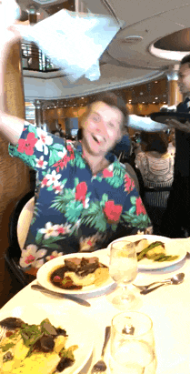 a man wearing a hawaiian shirt is sitting at a table with plates of food