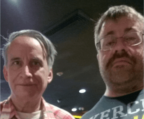 two men are posing for a picture with one wearing a shirt that says mercy