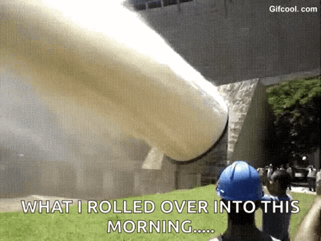 a man in a blue hard hat is standing in front of a large pipe that is being rolled over into this morning .