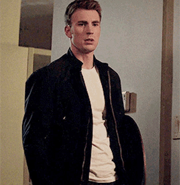 a man in a black jacket and white shirt is standing in a doorway .