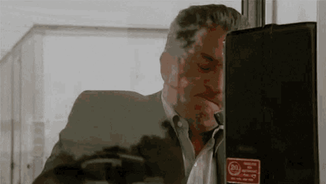 a man in a suit is smoking a cigarette while standing next to a door .
