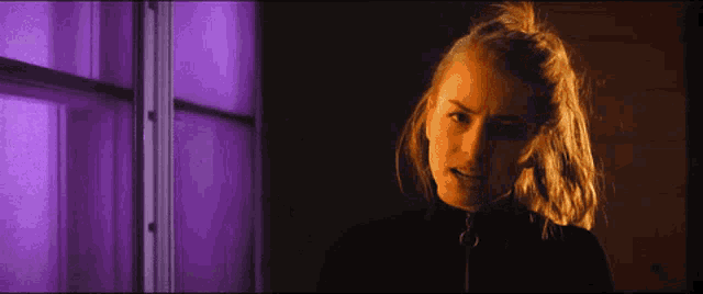 a woman is standing in front of a window with purple lights on it