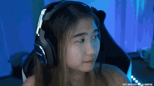 a woman wearing headphones with a blue background that says ' a ' on the bottom right