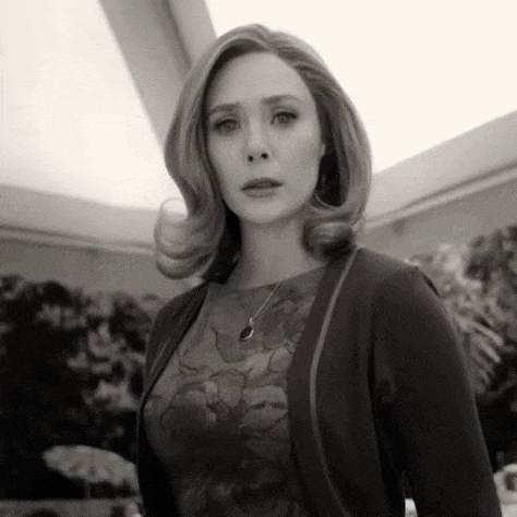 a black and white photo of a woman in a floral dress and cardigan .