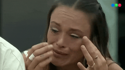 a woman is crying while a man wipes her face with a napkin .