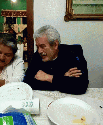 a man and a woman sit at a table with a bag of bella paper towels