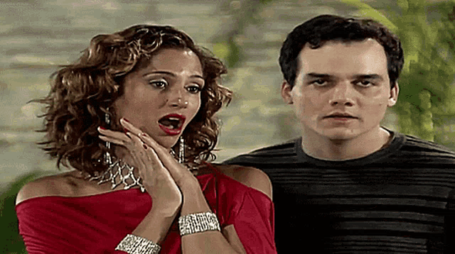a man and a woman are standing next to each other and the woman is wearing a red dress
