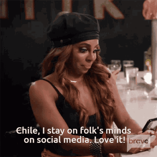 a woman is sitting at a bar looking at her phone and says chile