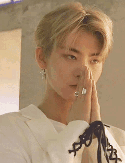 a young man with a ring on his finger is praying with his hands folded