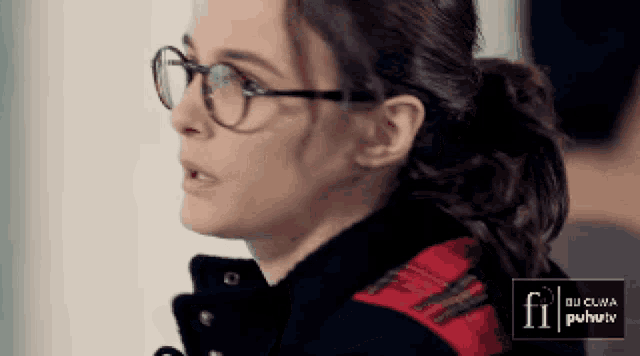 a close up of a woman wearing glasses and a plaid jacket with the word fi on it