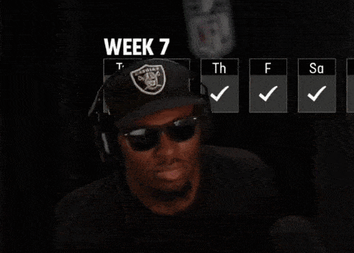 a man wearing headphones and a raiders hat is looking at the camera