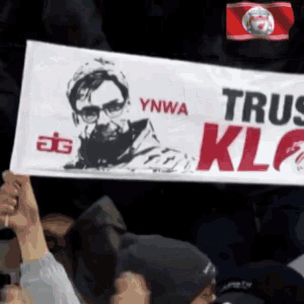 a man holds up a sign that says ynwa trus klf