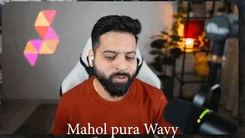 a man with a beard is sitting in front of a microphone with the words mahol pura wavy written on the bottom