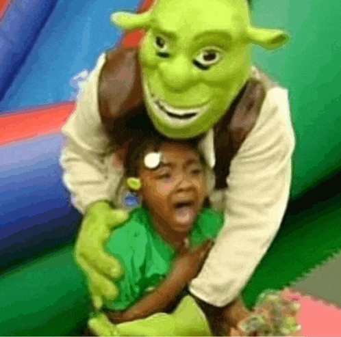 a person dressed as shrek is holding a little girl